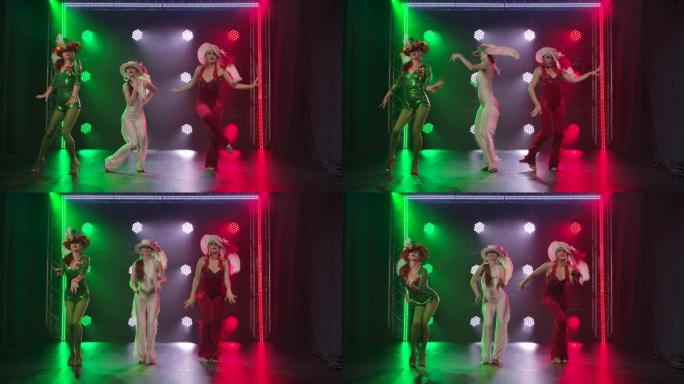三位穿着别致舞台服装的苗条优雅女士的戏剧表演。妇女在意大利国旗风格的绿色，白色和红色灯光的背景下跳舞