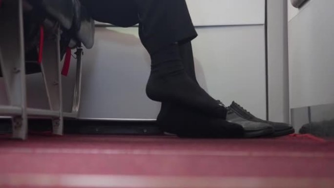 飞行中脚臭。飞机地板旁边的男人用鞋子抓脚。