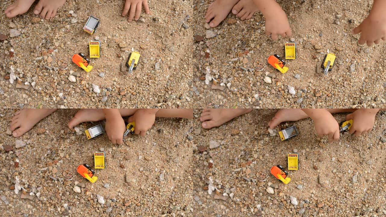 小男孩在沙滩上玩塑料玩具挖掘机