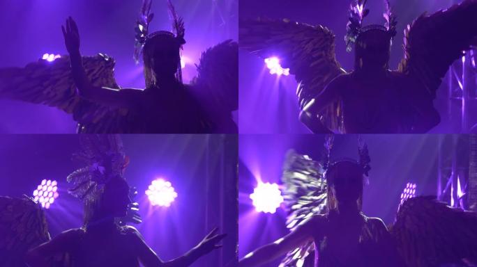 一个背上有翅膀的跳舞女人的剪影。希腊女神阿耳emi弥斯 (Artemis) 在带有紫色霓虹灯的戏剧声