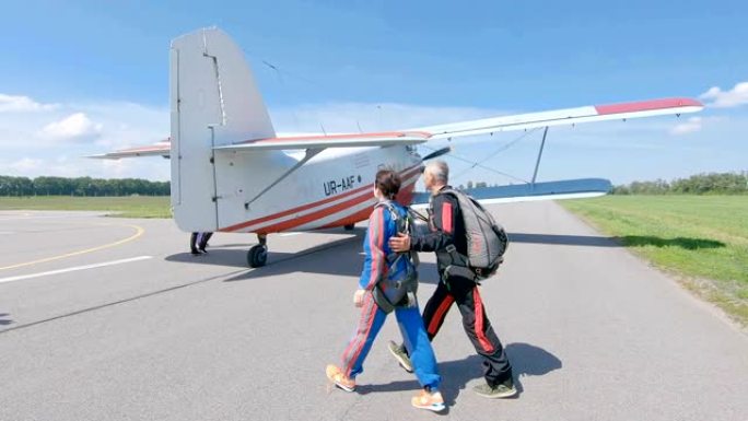 跳伞运动员在飞机场的跑道上登上飞机。