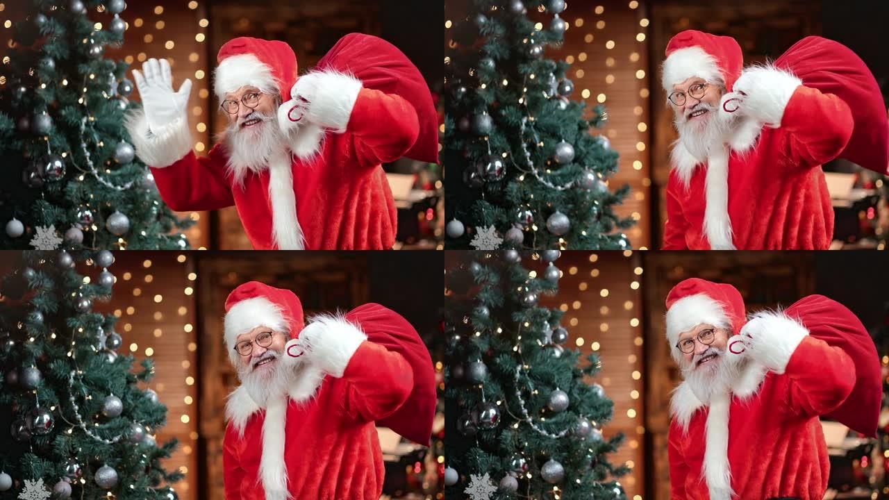有趣的男性圣诞老人背着礼品袋在圣诞树上挥手。红色相机上的中等镜头