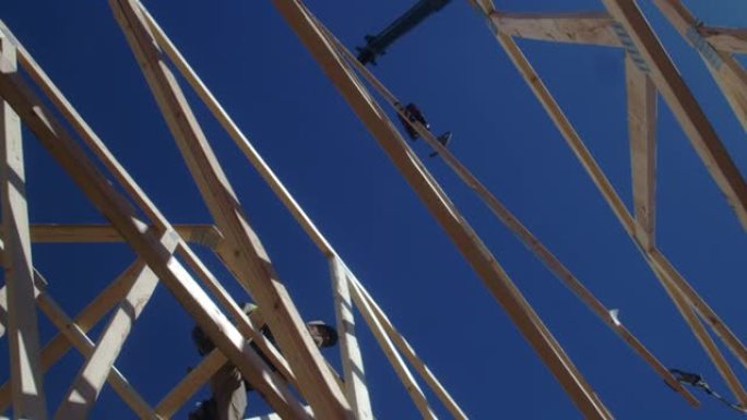 在正在建造的新房子上安装桁架的装帧者的空中无人机视图