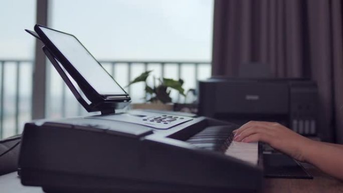 一个年轻的亚洲女孩少年的手拍正在她的房间里练习钢琴键盘音乐。