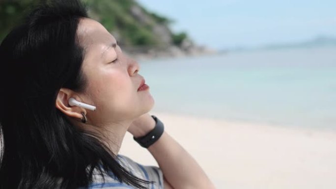 暑假时间在海滩用手机听音乐关闭快乐的亚洲女人