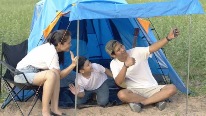 快乐的亚洲家庭父母和孩子用您的手机拍照，度假时要去露营。