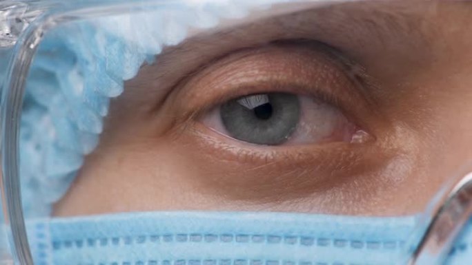 女医生半脸，眼睛戴着安全眼镜。健康员工看着相机。肖像医学研究者女性在医院或诊所佩戴防护装置和护目镜。