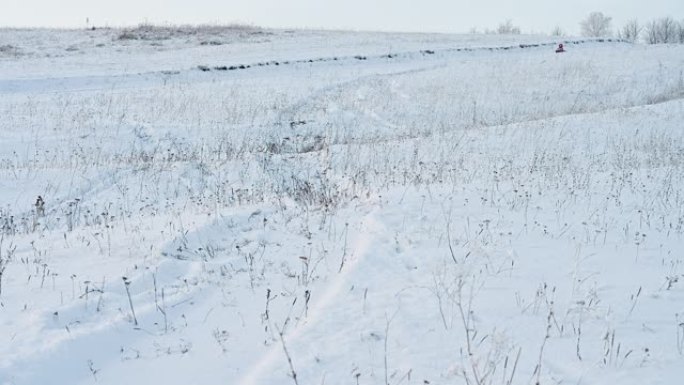 小女孩骑在户外小山上的充气雪橇上