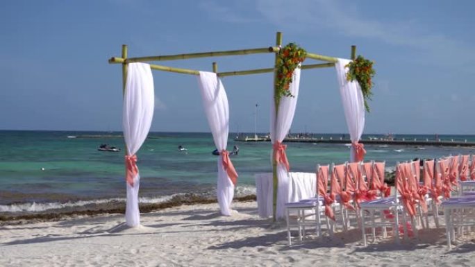 在热带海滩上装饰有鲜花和大型风力织物的婚礼拱门。加勒比海的绿松石水。墨西哥里维埃拉玛雅