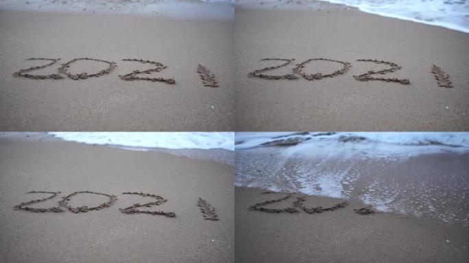 波浪冲走了沙子里2021的数字。新年快乐2022来了。新年2022即将到来的概念-沙滩上的数字。20