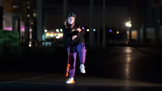 开朗的年轻女子在夜间在城市街道上以彩色背光跳舞嘻哈，自由泳或赃物