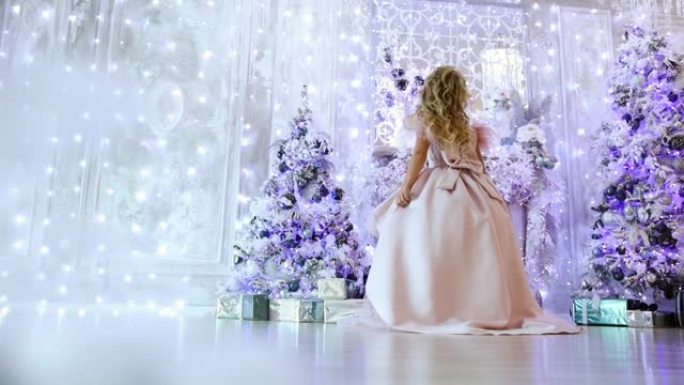 小女孩在圣诞树的背景下穿着舞会礼服旋转