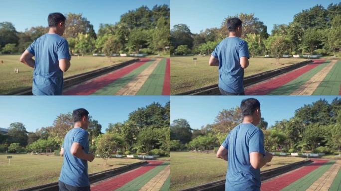 在阳光明媚的日子里，亚洲中年男子在公园的跑步道上慢动作奔跑。退休健康生活方式活动。保健动机概念，身体