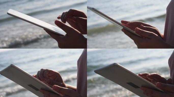 在度假期间，用数字平板电脑对抗海滩上的日出，生活方式概念。