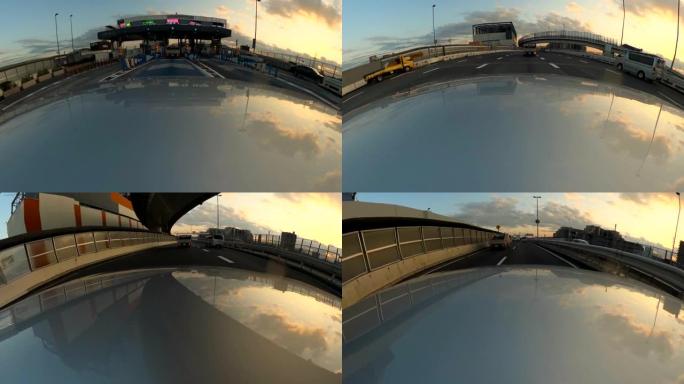 黄昏时在高速公路上开车。经过收费站。汽车引擎盖上的摄像头。动作相机拍摄。