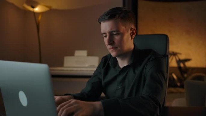 一名男子在笔记本电脑键盘上打字，并在家庭内部接听电话