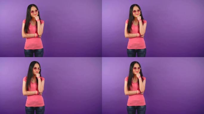 困惑的年轻亚洲女子戴着明亮的太阳镜，在做出选择时左倾右倾。孤立的紫色背景。4K
