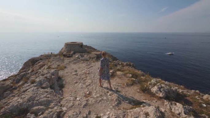赤脚女人走在石质斗篷上。意大利海岸的晴天