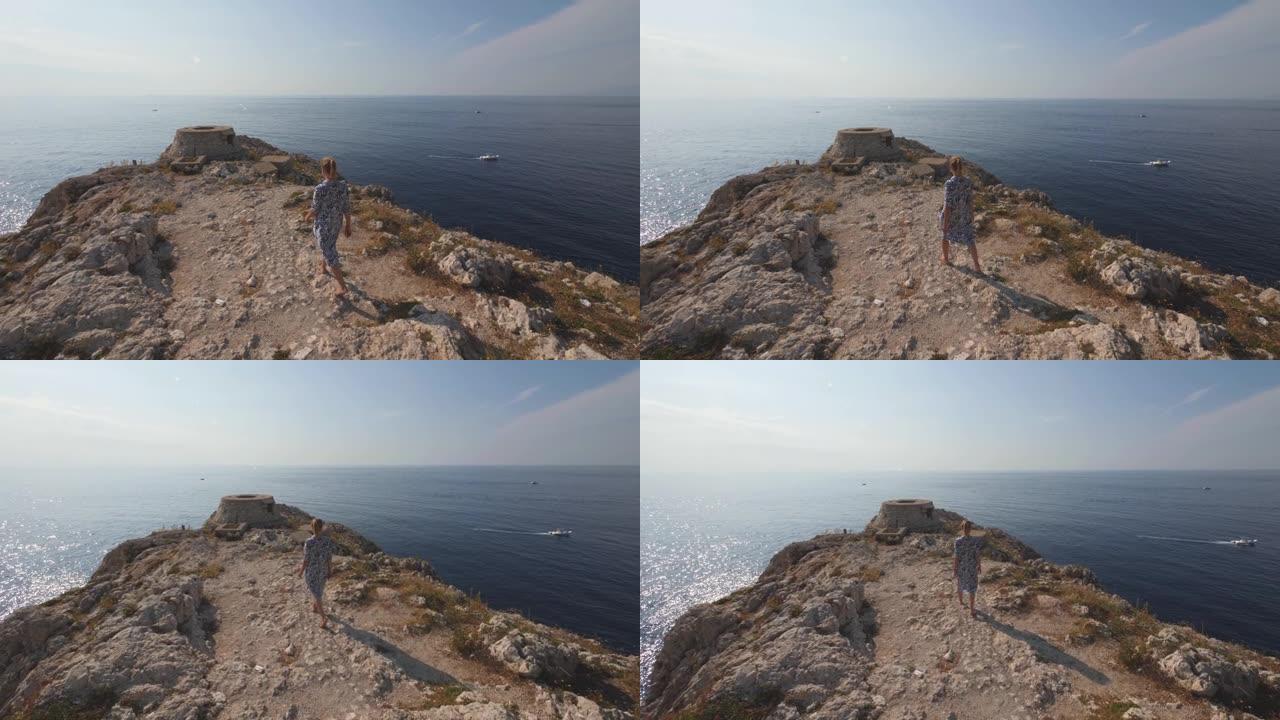 赤脚女人走在石质斗篷上。意大利海岸的晴天