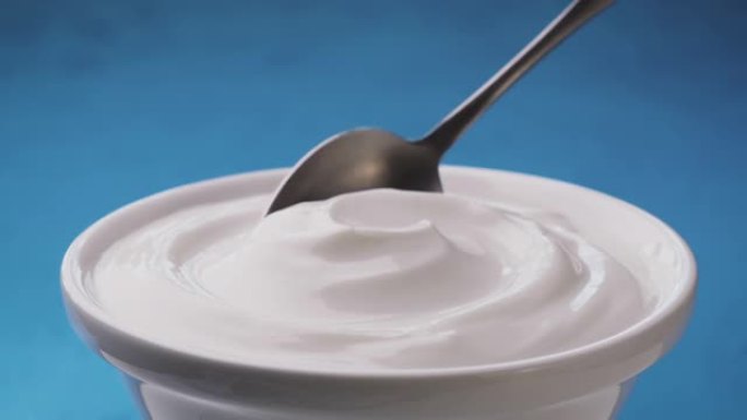 一碗蓝色背景的酸奶油，希腊酸奶