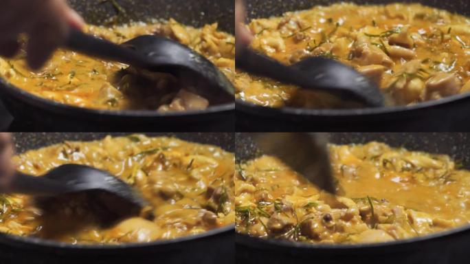 有人在黑锅上搅拌沸腾的panang咖喱。泰国菜配鸡肉菜单。宏观平移拍摄。