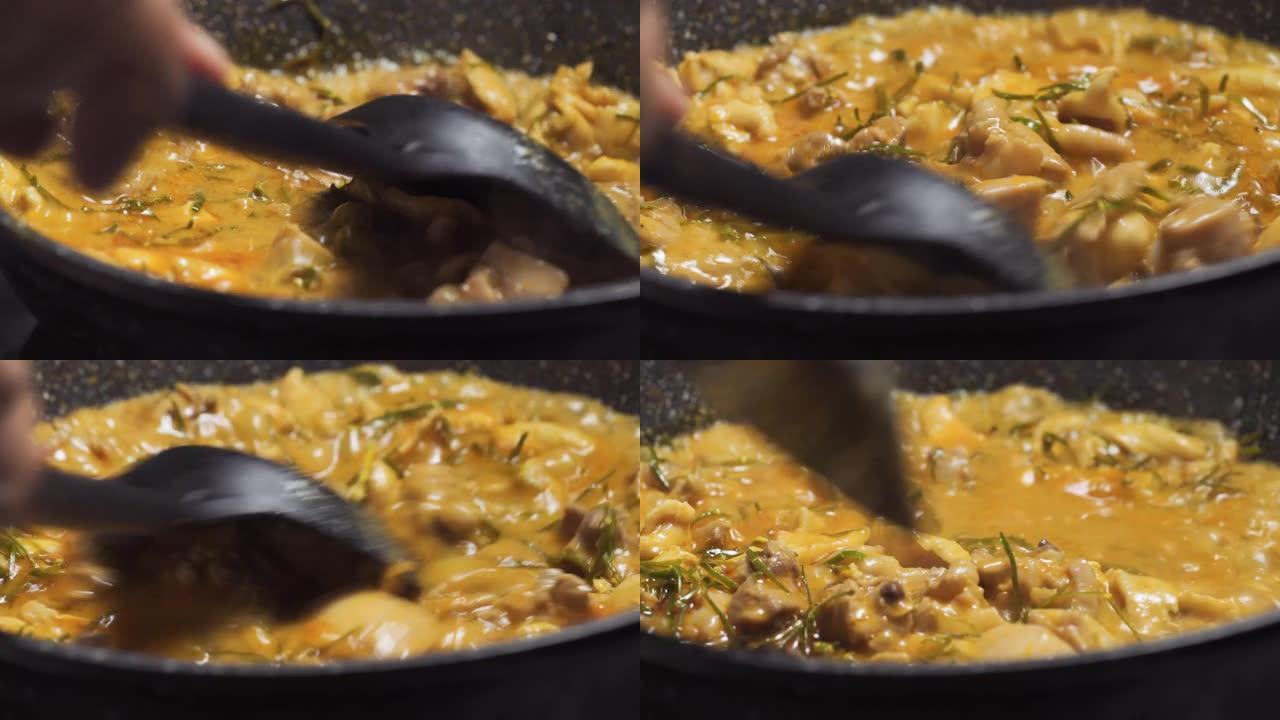 有人在黑锅上搅拌沸腾的panang咖喱。泰国菜配鸡肉菜单。宏观平移拍摄。