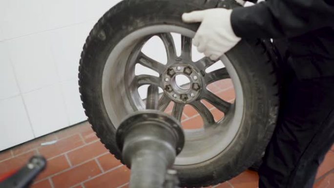 轮胎服务。维修人员在服务站安装带有特殊装置的轮胎。钢盘上汽车轮胎的更换