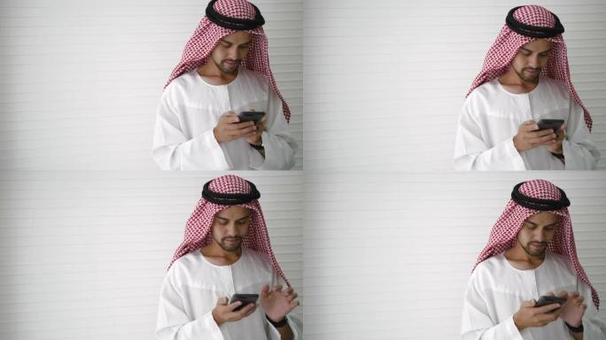 阿拉伯商人专业持有现代智能手机，用于浏览互联网查找社交信息或下载应用程序。在新常态下，在社交距离之间