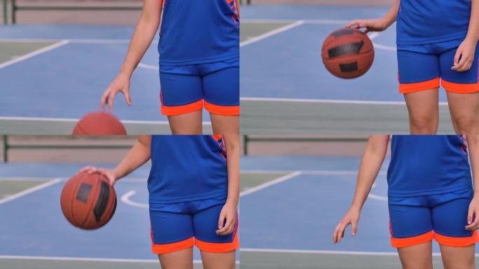 一个穿着蓝色制服的少女用球击中地面。夏季户外篮球练习。练习运球。青年体育生活理念。特写。慢动作