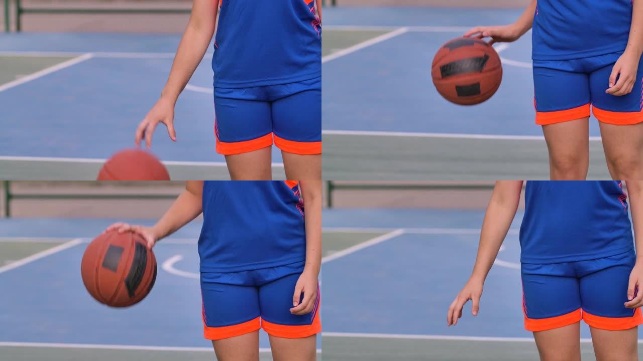 一个穿着蓝色制服的少女用球击中地面。夏季户外篮球练习。练习运球。青年体育生活理念。特写。慢动作