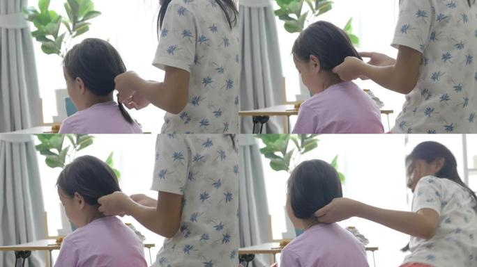 手亚洲女孩在家里编织姐姐头发，孩子们在一起玩得开心，生活方式理念。
