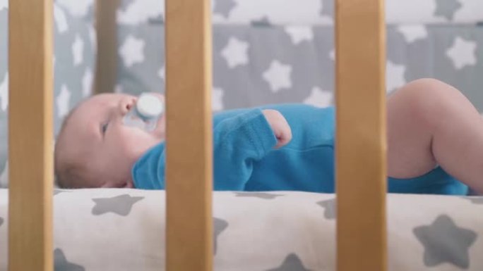 小男孩吮吸躺在舒适婴儿床上的假人