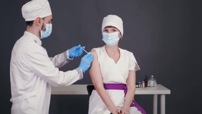 冠状病毒医疗人员、医生的疫苗接种。护士戴着防护口罩和医用手套，用疫苗注射器给医生接种疫苗。新型冠状病