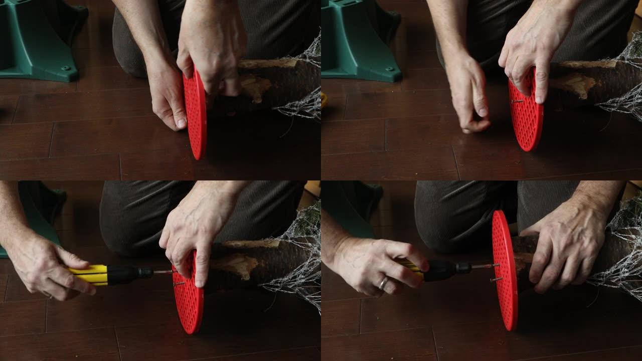 男子用螺丝刀将圣诞树固定在塑料底座上的镜头