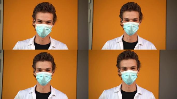 新型冠状病毒肺炎爆发期间，年轻男性医生戴着口罩靠在墙上的特写肖像。高质量4k镜头