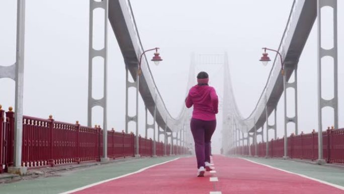 年轻胖乎乎的高加索女孩在桥上奔跑。回击。紫色套装