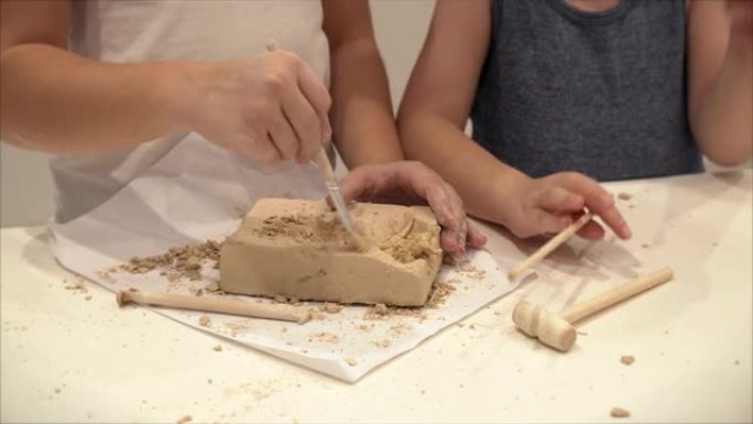 孩子们的手，孩子们的特写镜头从一块粘土中扮演多古学家，挖掘出恐龙的儿童教育圈进行绘画和建模。4-9岁