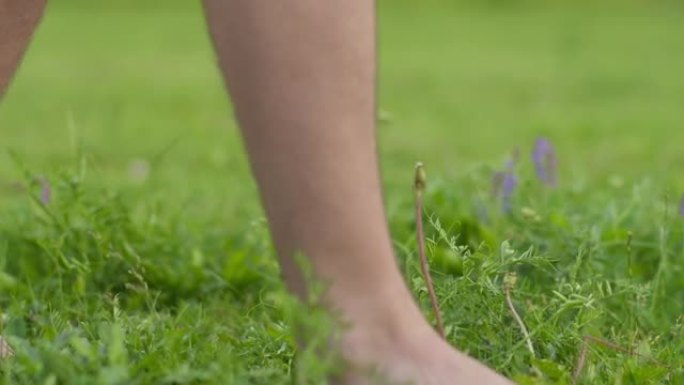 一个男人赤脚走在绿草地上，镜头移动，特写