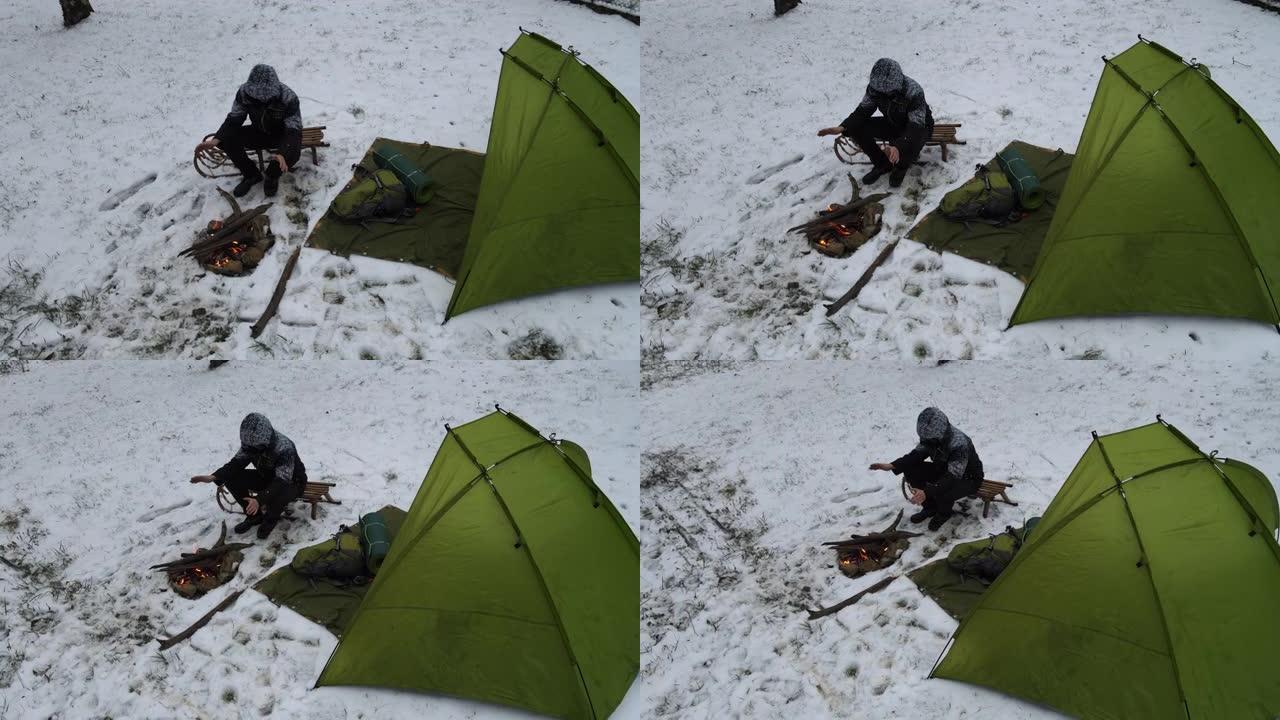 成年男子在冬季自然露营时在篝火旁热身和放松