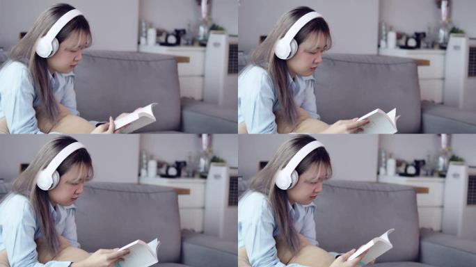 一个亚洲少女用耳机听音乐，在客厅背景中看书