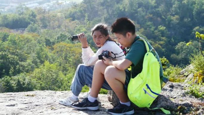 亚洲儿童在山顶上使用双筒望远镜和相机一起，冒险概念。