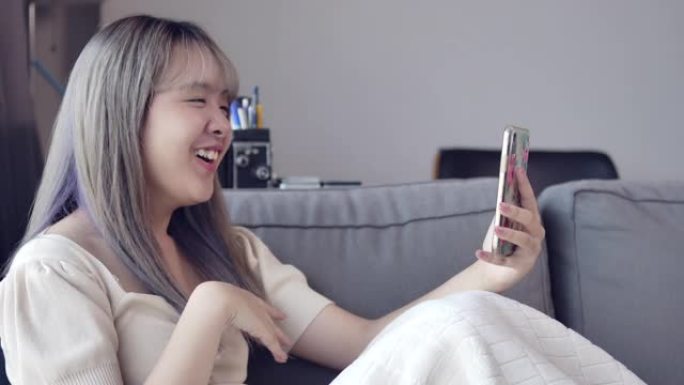 在检疫期间，一名亚洲少女正在通过智能手机的视频通话与朋友交谈。