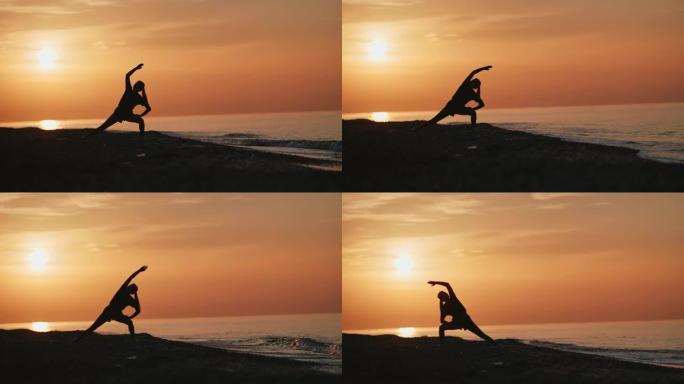 健身女子在海滩上练习体式瑜伽姿势的剪影。4k龙红相机