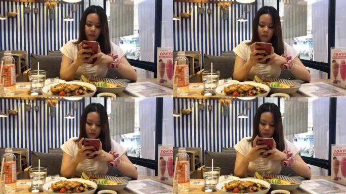亚洲少女在餐厅吃饭时使用智能手机摄像头
