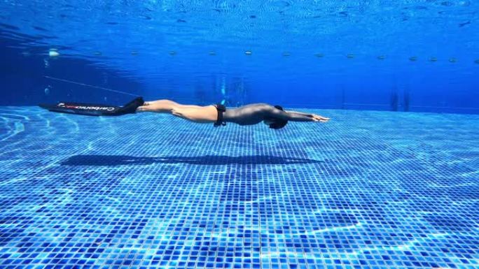 水下景观跟踪女人穿一件长袖比基尼剪裁潜水服做海豚踢鳍游泳动态呼吸暂停与双鳍在游泳池