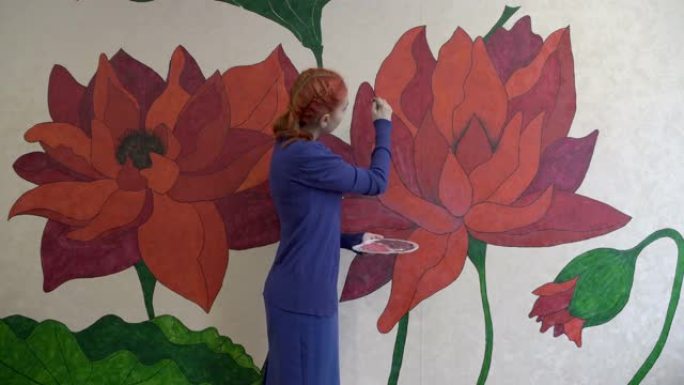 一个美丽的红发艺术家女孩在她房间的墙上画了大童话般的花朵。由于冠状病毒大流行，检疫时期自我实现的概念