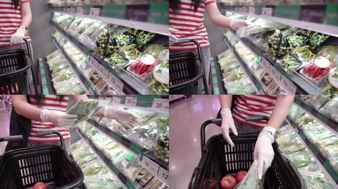 女人的手戴着防护手套，在杂货店选择蔬菜。