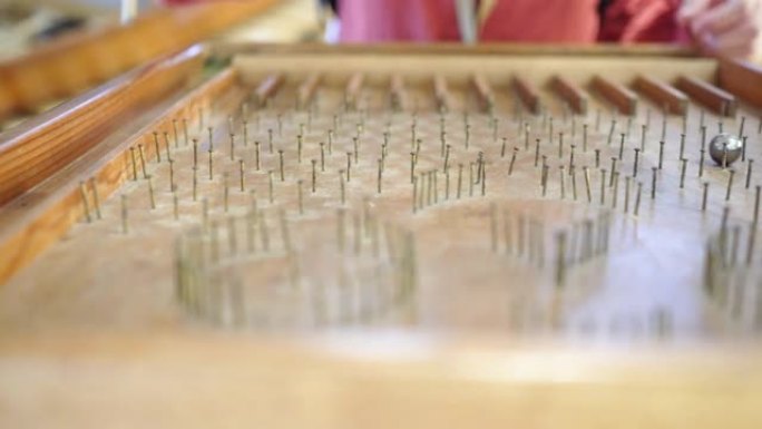 在木头做的弹珠台上特写。玻璃珠在弹珠台上滚落。一个孩子玩的游戏。主题在左边。