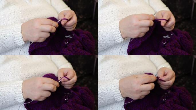 女人用织针编织夹克。女人的手和编织特写。