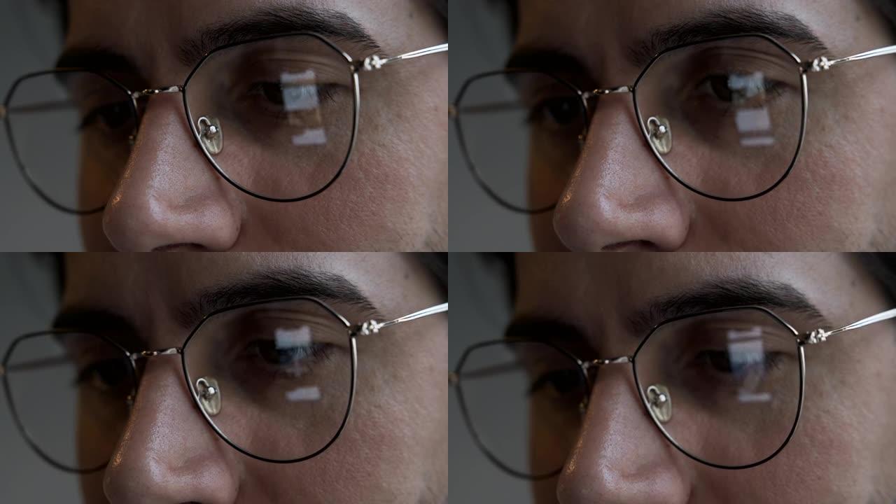 一个戴着眼镜的男人的特写镜头在智能手机上观看新闻，镜头上的反射，家里的暗室